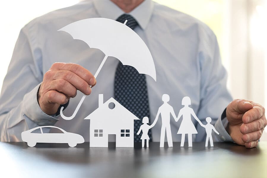 What is an Umbrella Insurance Policy? - Family, Home and Car Protection Under a Cut Out of an Umbrella Held by a Man in a Suit in the Kitchen
